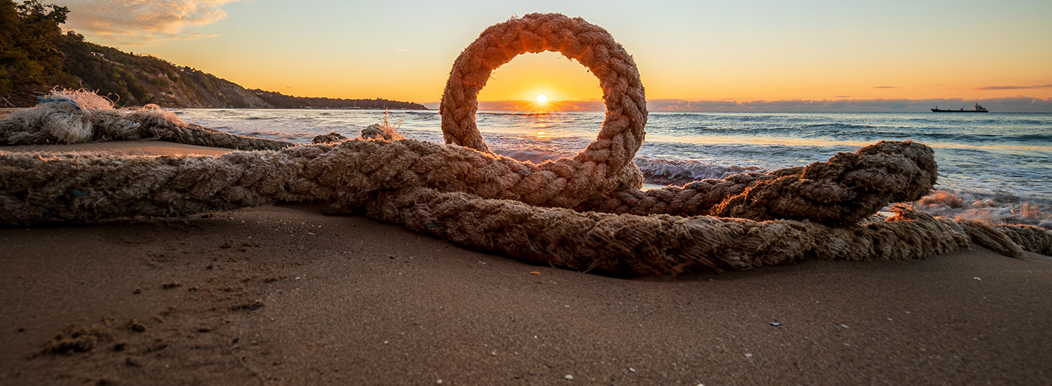 Atardecer en una playa enfocado a través de una cuerda.