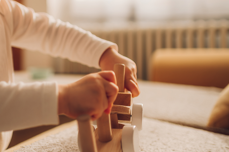 Niño jugando con juguete de madera. Referencia a infancia.