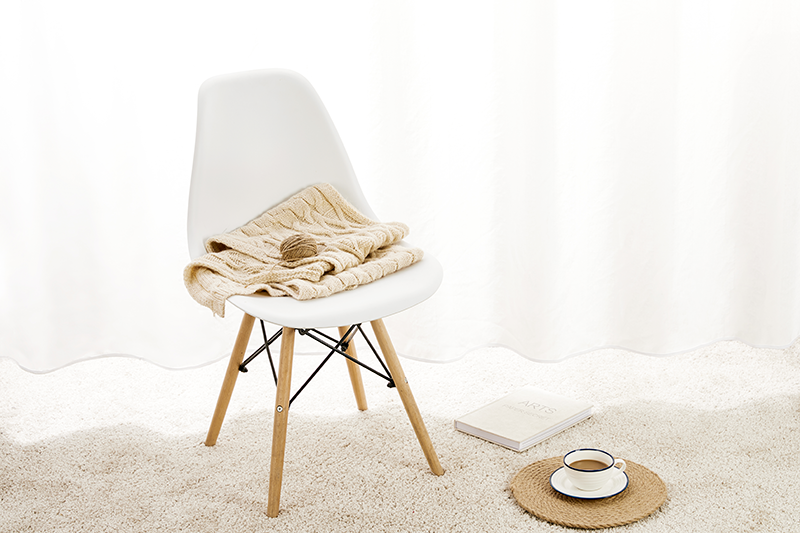 Silla con una prenda de lana, un libro y un café.